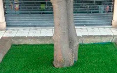 UNA COMUNIDAD DECORA LA BASE DE SUS ÁRBOLES CON CESPED ARTIFICIAL